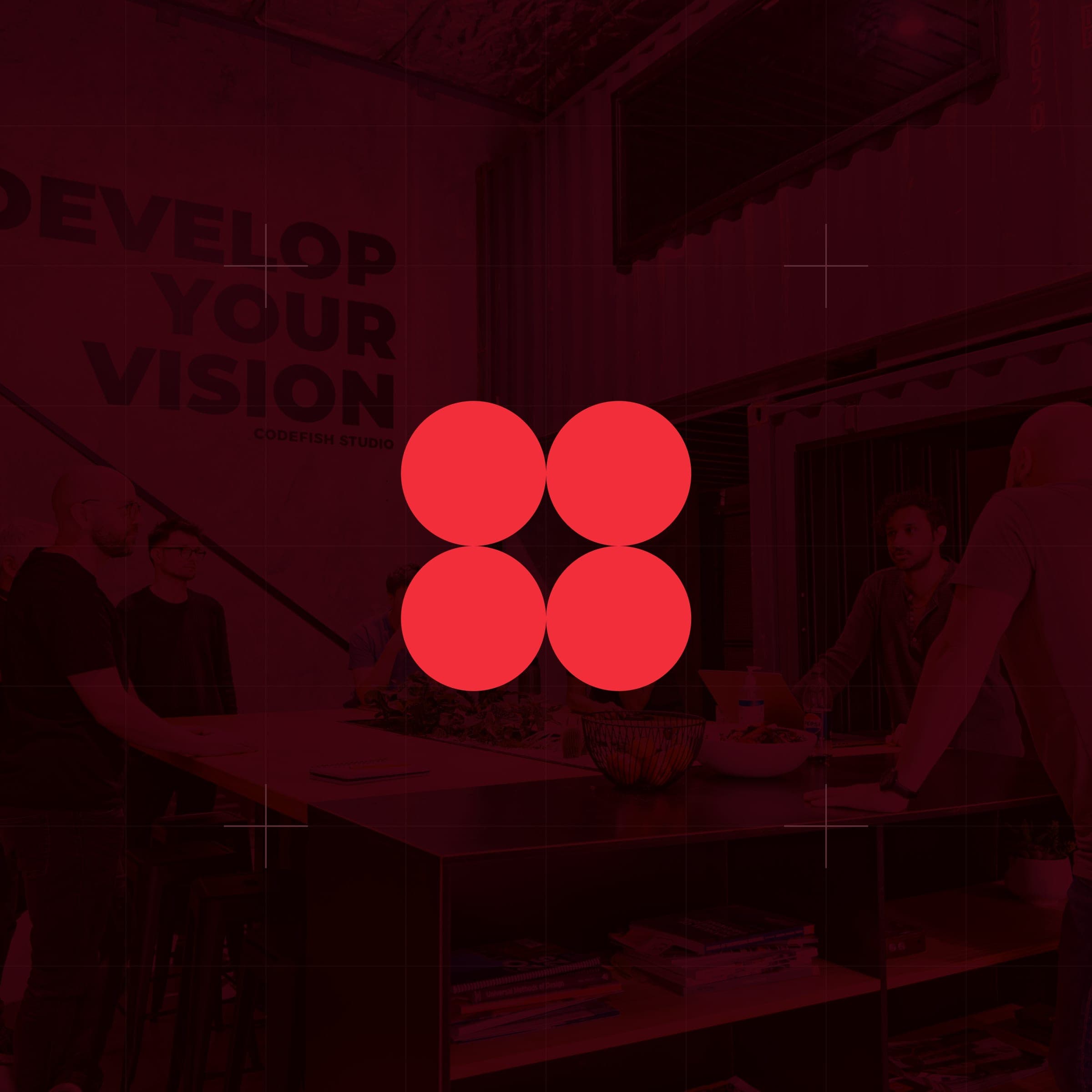 CodeFish Studio four-dot glyph over a red-tinted studio scene with a Develop Your Vision wall